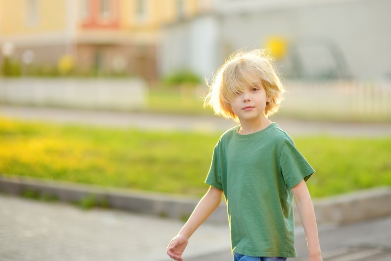 A young boy walking outdoors alone.