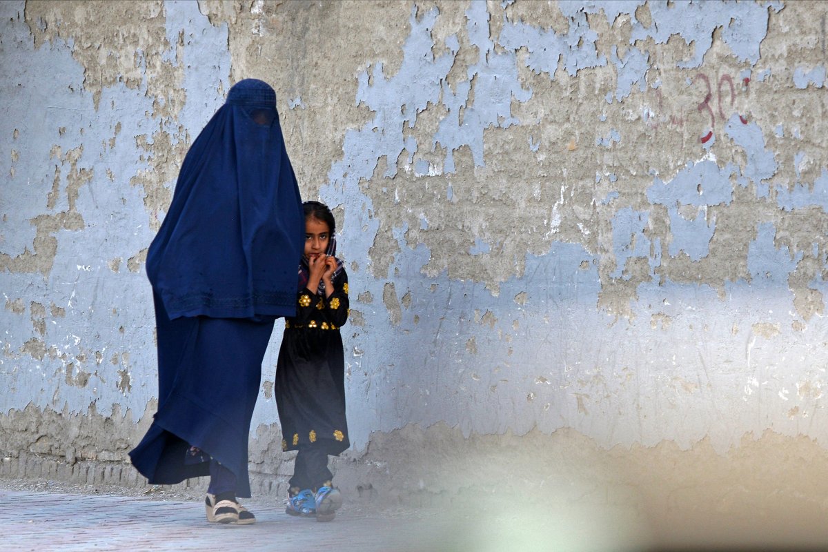 A burqa-clad woman walks with a girl 