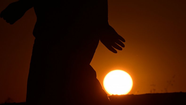 A hiker walks past the setting sun 
