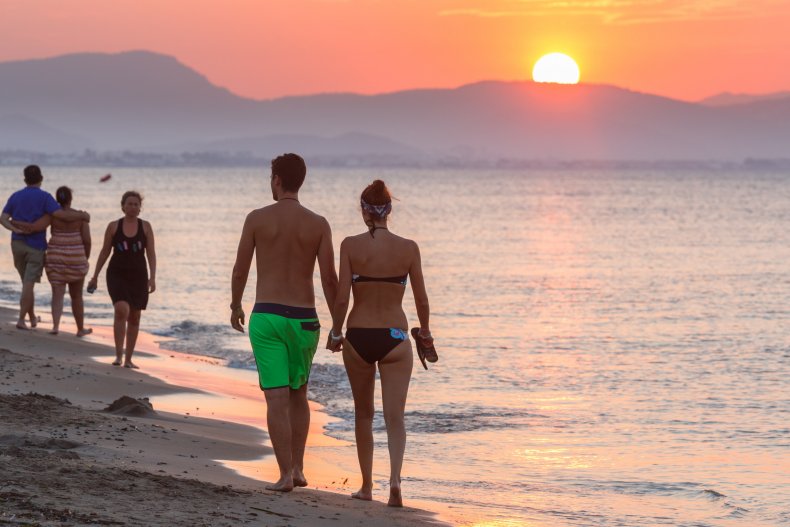Couple walking along beach sunset in Spain.