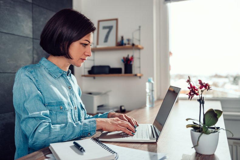 Woman at desk, typing on a laptop.