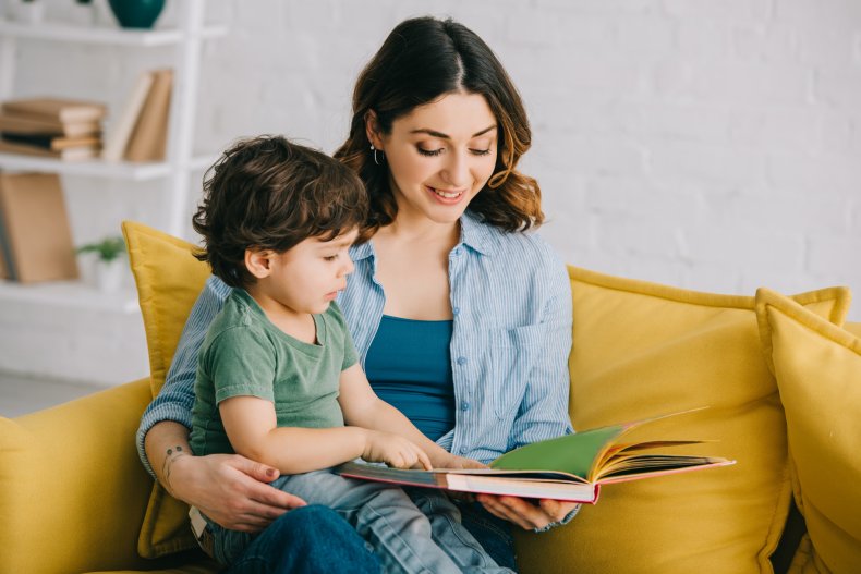 A woman reading a book to toddler.