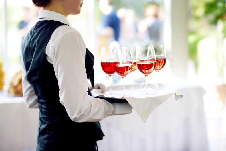 Waitress holding wine glasses at wedding reception.