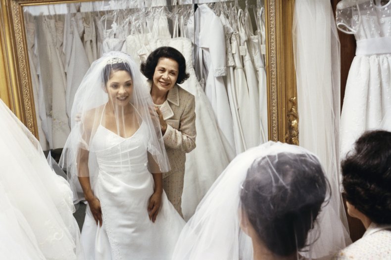 Bride and mother trying on dress