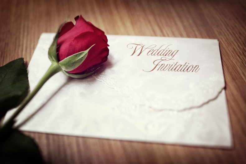A rose next to a wedding invitation. 