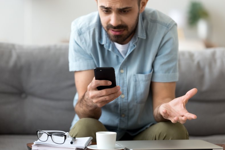 Man looking down at phone in horror