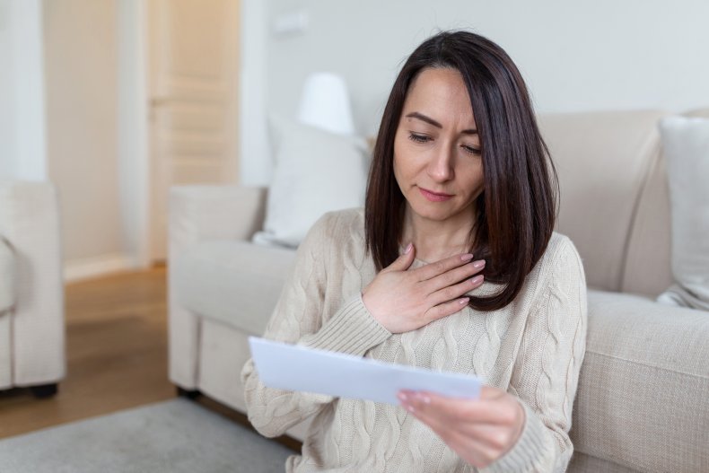 A middle-aged woman anxiously receiving a letter