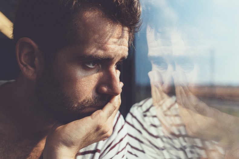 Man looking sad, looking out window.