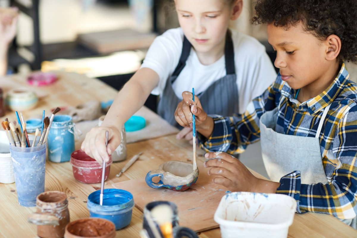 Young boys painting ceramics in a classroom.