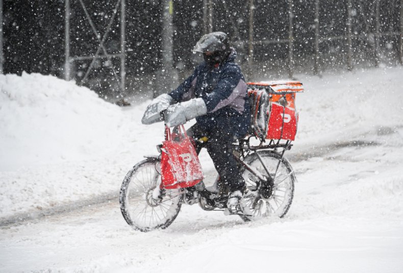 A DoorDash delivery person rides a bicycle