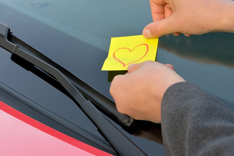Man leaving a love note on someone's car