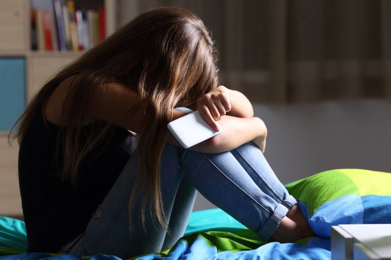 A teenager/young woman crying on her bed