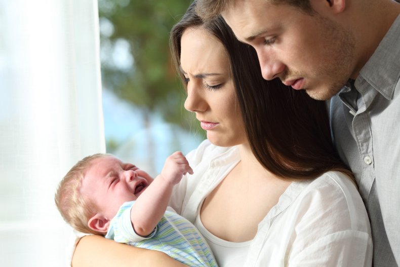 Couple holding crying baby. 