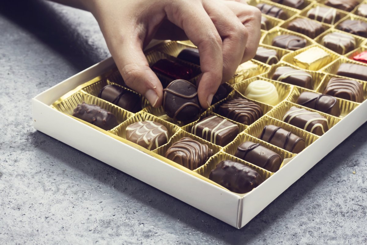 Woman's hand dipping into a chocolate box