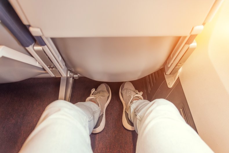 Legs of airline passenger on seat.