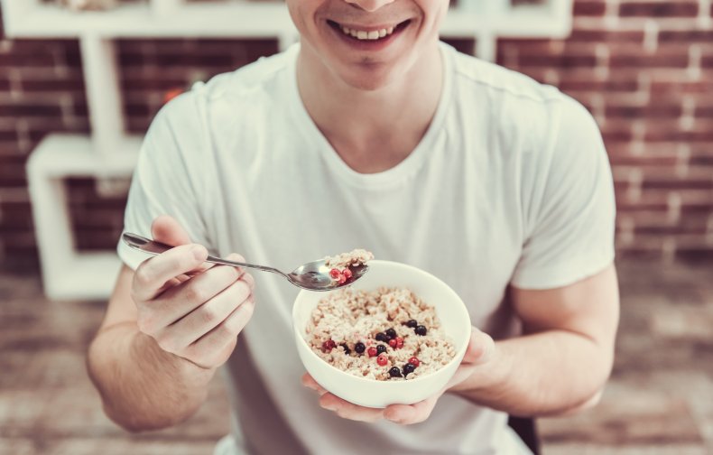 A man eating a bowl of oatmeal with fruit.