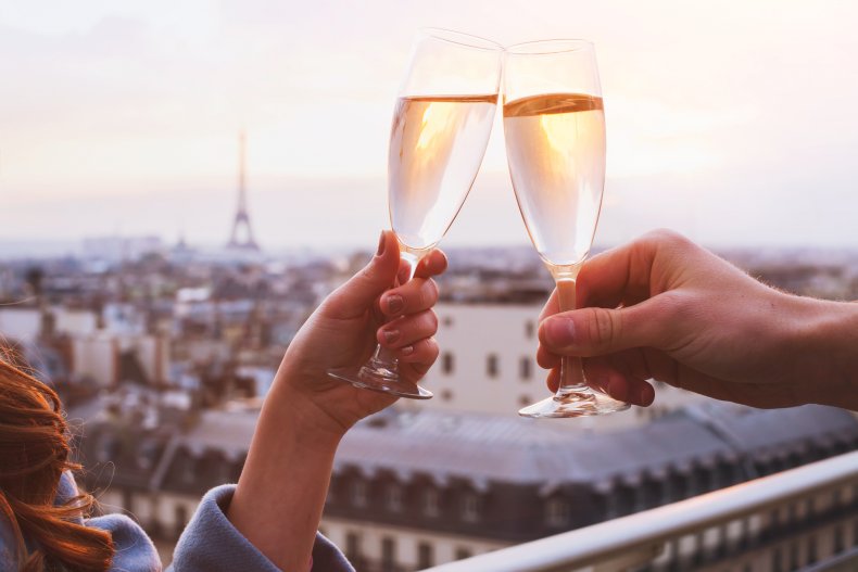 Couple clinking champagne glasses on Paris balcony