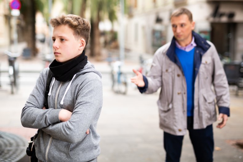 Adult man looking at young boy outdoors.