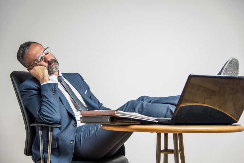 Office worker sleeping, with feet on desk.