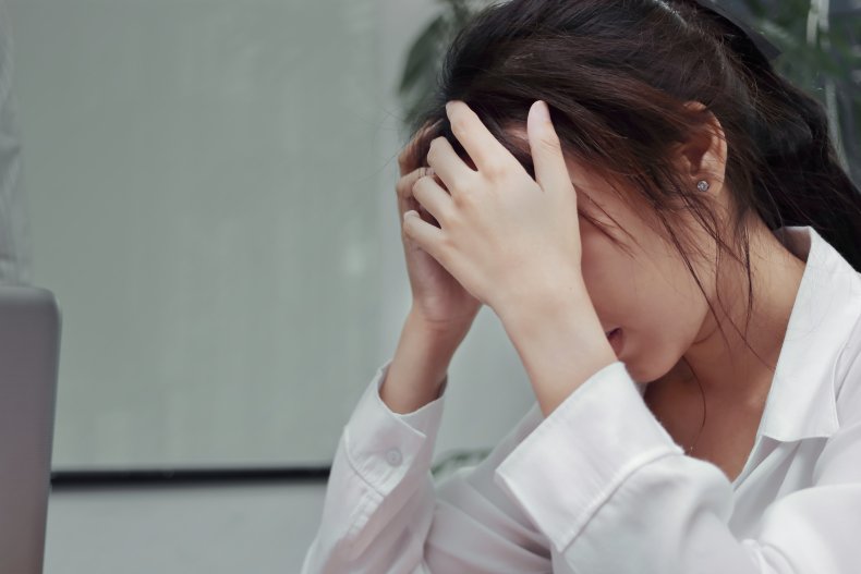 Depressed office worker crying into her hands