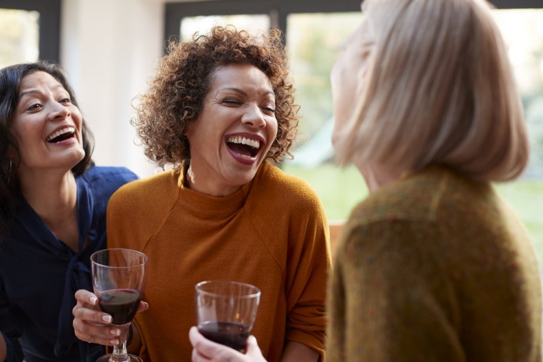 Three older women laughing and drinking.