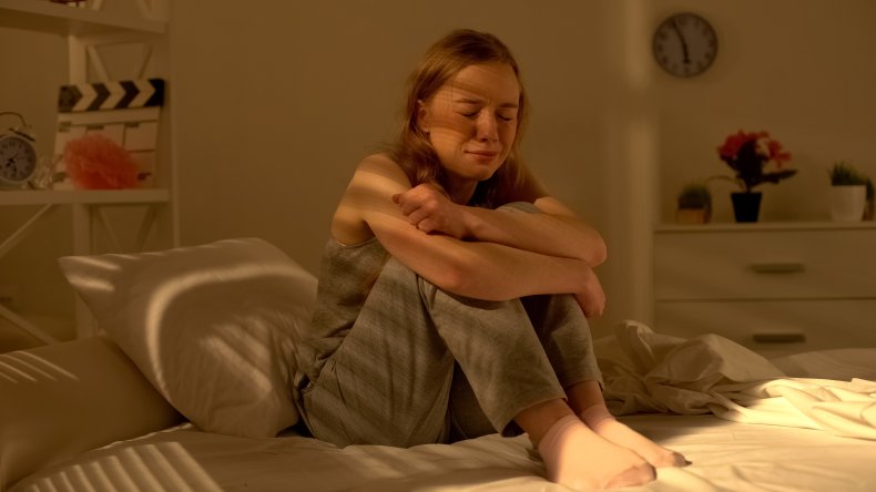 A teenage girl crying on her bed
