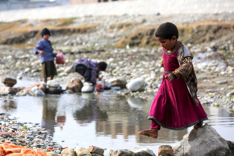 An Afghan girl walks across a stream 