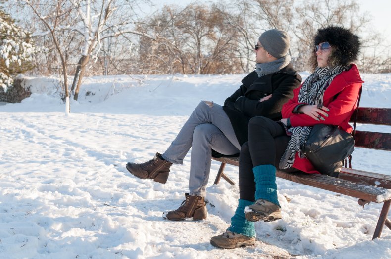 Angry couple sitting on bench in snow