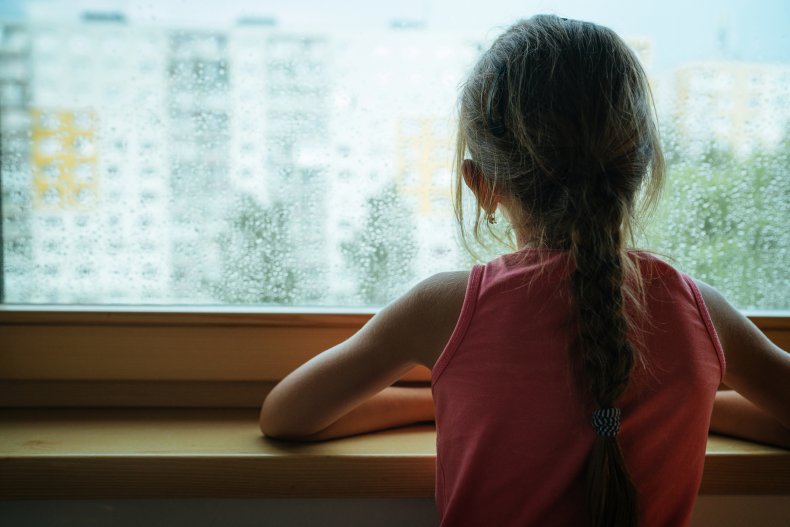 Girl looking out of a rainy window
