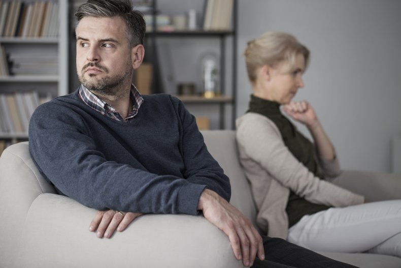 Middle-aged couple ignoring each other on sofa