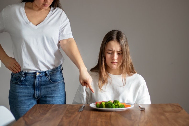 Disgruntled teenage girl staring at vegetable plate