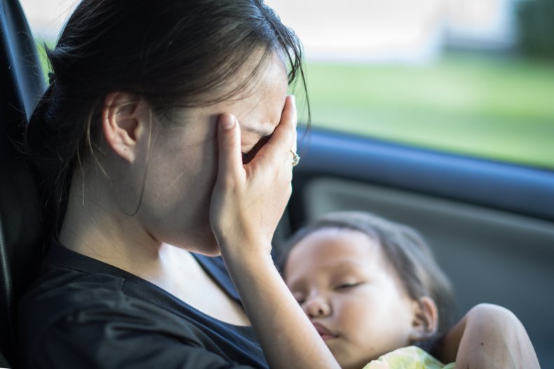 Mother crying in car while baby sleeps