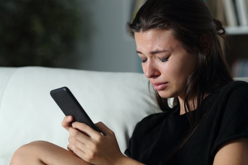 A young woman crying while texting