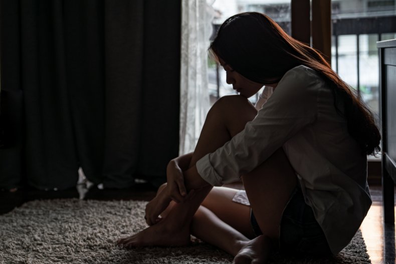 Young woman sitting curled up on floor