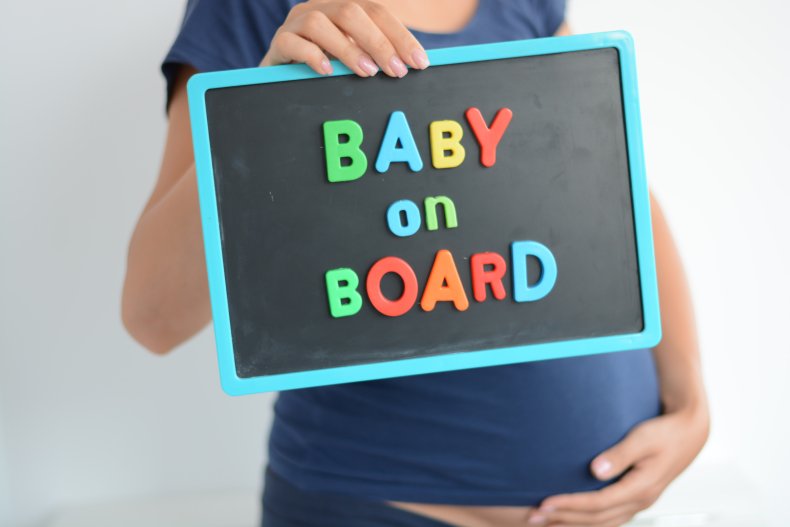 Pregnant woman with "baby on board" sign.