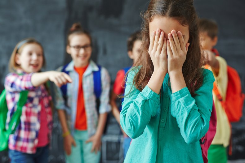 Crying young girl being bullied in classroom