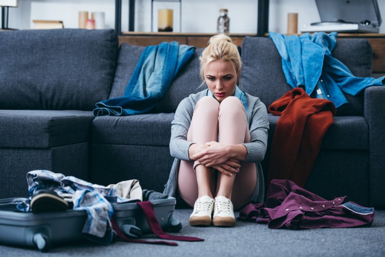 Upset young woman surrounded by clothes