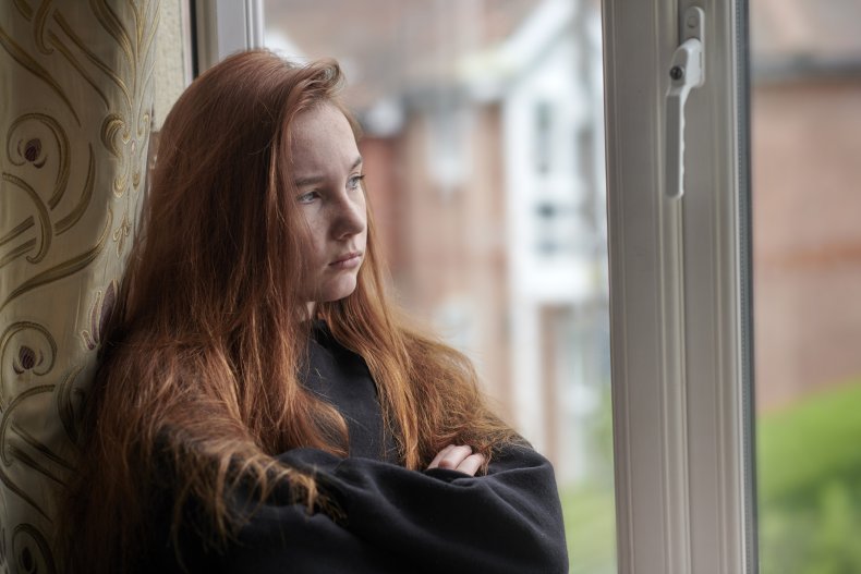 Teenage girl looking upset, looking out window.