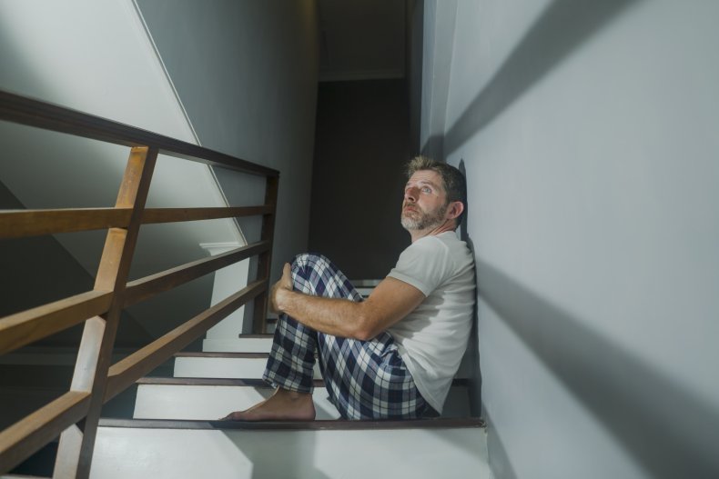 Man looking upset on stairs at home.