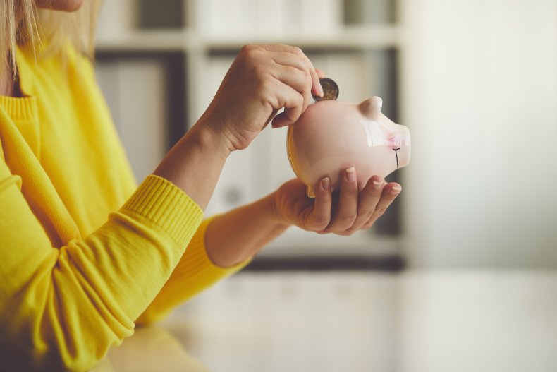 Woman's hand putting coin into piggy bank