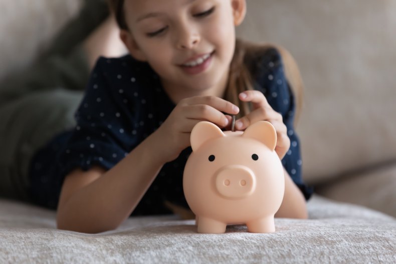 Young girl putting coin into piggy bank