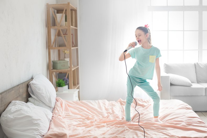Girl singing with a microphone on bed