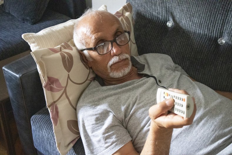 Elderly man lying on couch watching TV