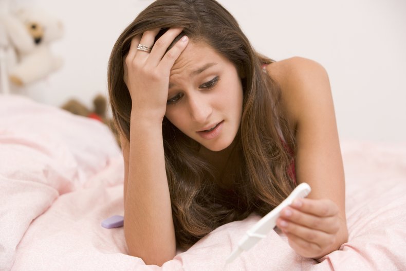 Upset teenage girl looking at pregnancy test