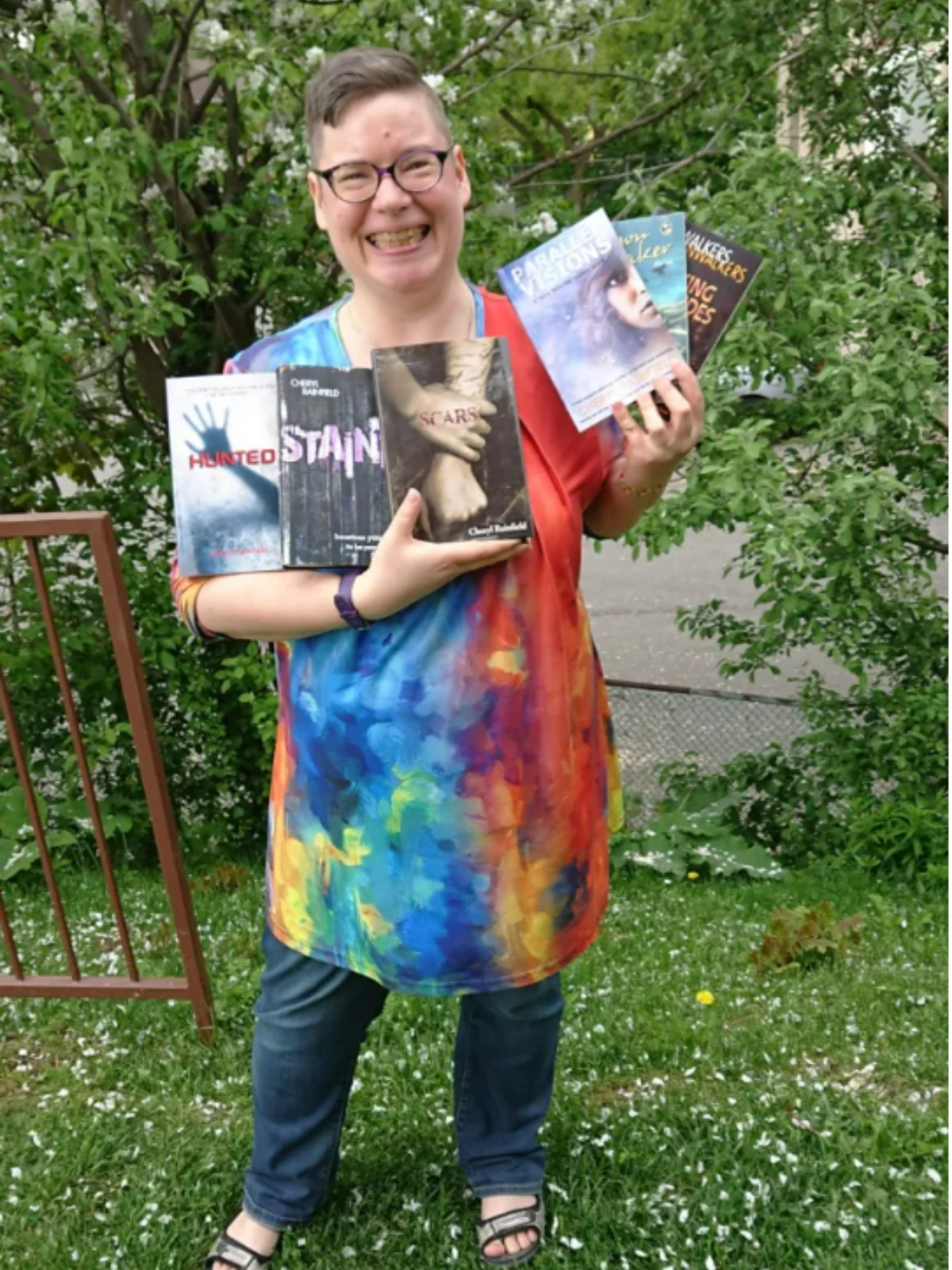 Cheryl Rainfield holding 6 of her novels