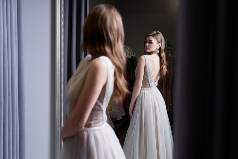 Woman wearing prom dress looking at mirror.