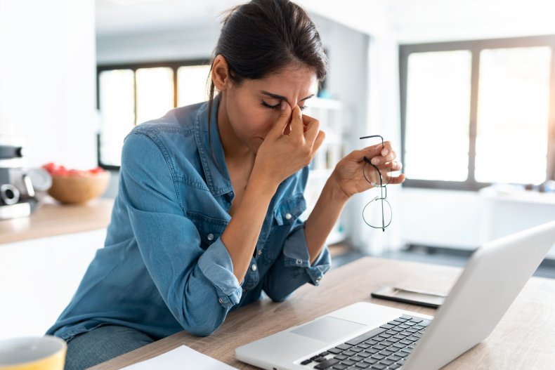 Woman with hand on head at desk.