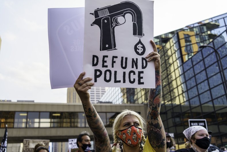 A protester holds a sign that reads "defund 