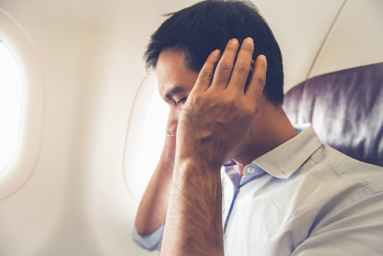 Man covering his ears on a plane.