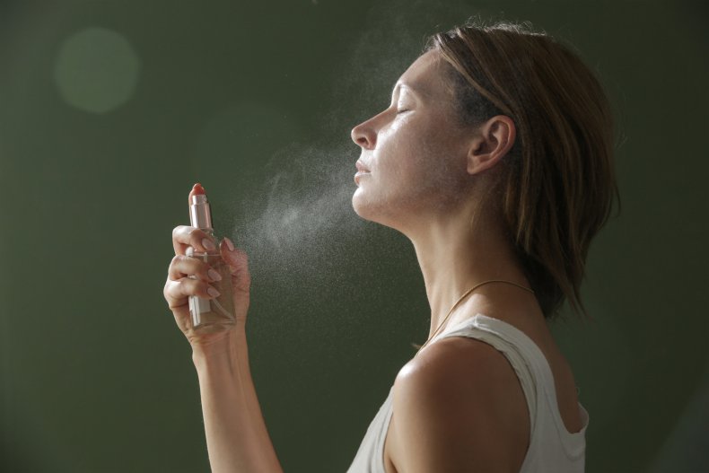 Woman spraying mist on her face.
